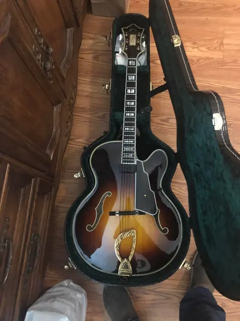 A sunburst archtop jazz guitar resting in its open case